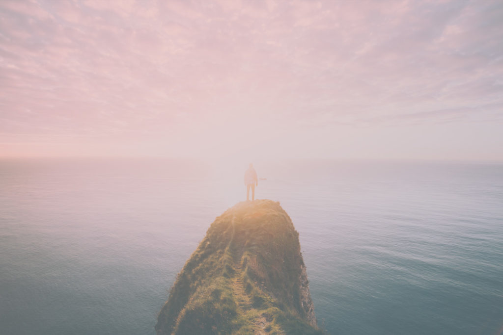 Man on cliff overlooking ocean