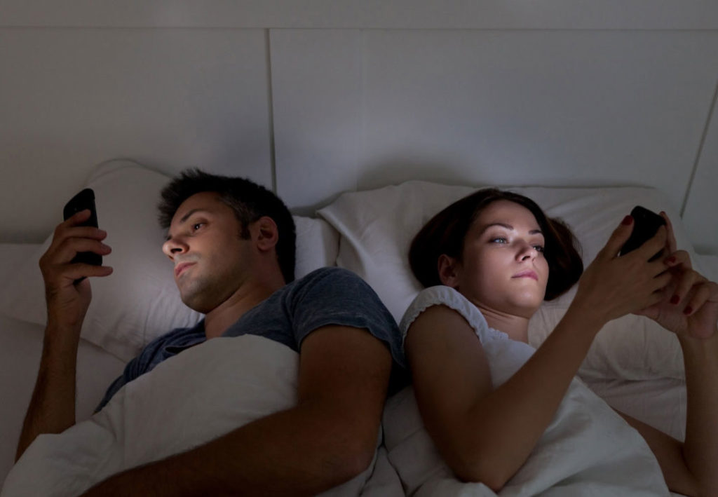 Couple in bed on their phones